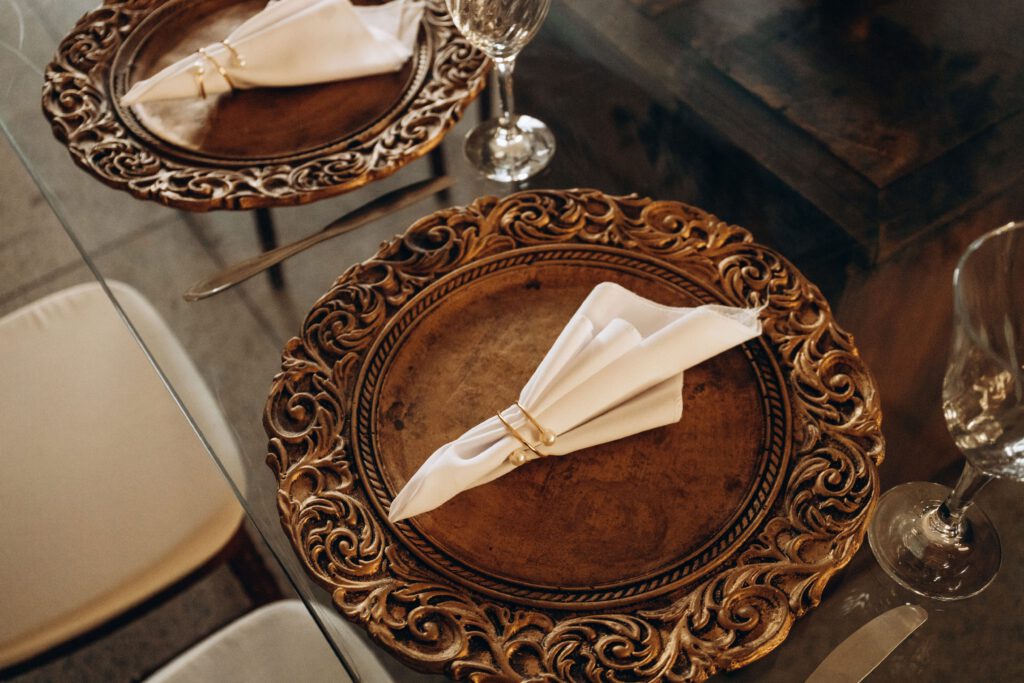 Luxurious dining table with bronze ornate plates and folded napkins, exuding elegance.