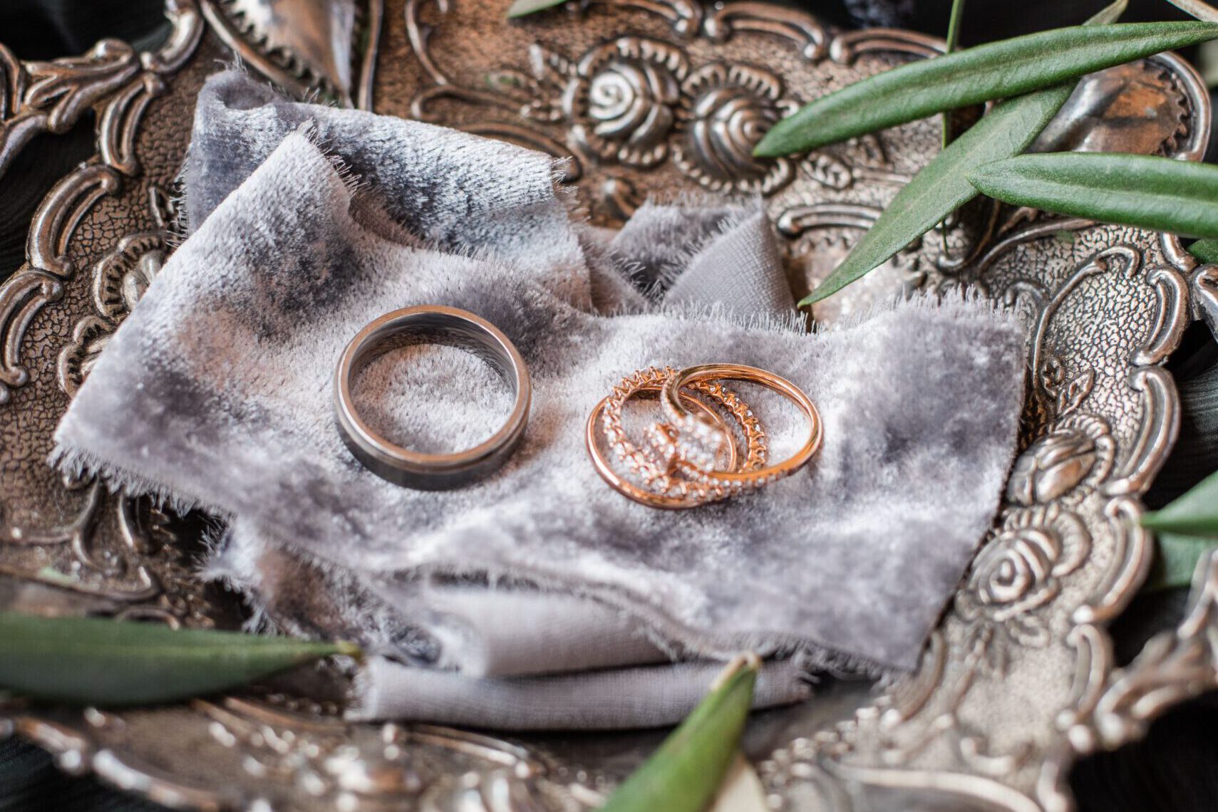 Ornate silver plate with gold and silver rings surrounded by greenery, exuding elegance and luxury.